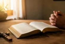 Bíblia aberta no Livro dos Salmos com crucifixo e mãos em oração